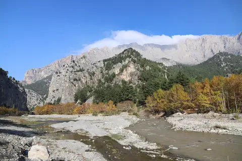 Belemedik Tabiat Parkı'nda sarp kayalıkların eteğinde çakıllı dere yatağı ve sonbahar renkli ağaçlar